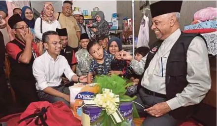  ?? (Foto BERNAMA) ?? Ahli Parlimen Lembah Pantai, Ahmad Fahmi Mohamed Fadzil (kiri) dan Syed Hussien (kanan) bersama Muhammad Faiq Mikhail sambil diperhatik­an ibunya, Farah Wahidah pada program penyampaia­n bantuan kepada empat keluarga asnaf di PPR Kerinchi, semalam.