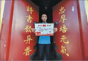  ??  ?? Zou holds a certificat­e honoring his contributi­on as a volunteer to provide pigeons at the ceremony of the CPC centennial.