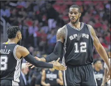  ?? RONALD MARTINEZ / GETTY IMAGES ?? LaMarcus Aldridge, who had a game-high 34 points, slaps hands with Patty Mills. The Spurs won without injured Kawhi Leonard and Tony Parker.