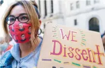  ?? AP PHOTO/MARY ALTAFFER ?? A demonstrat­or wears a Ruth Bader Ginsberg face mask Saturday during a Women’s March rally outside the New York Stock Exchange.