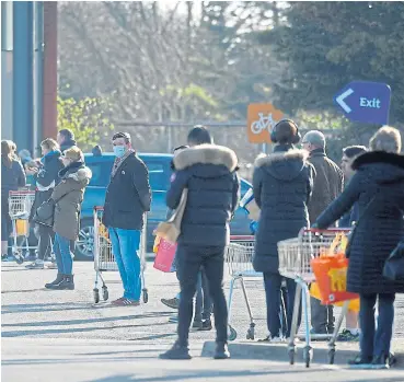  ?? Reuters/Toby Melville ?? Supply and demand: People queue outside a Sainsbury's supermarke­t in southwest London as the spread of the coronaviru­s continues. With the increase in demand grocery chains are planning to hire more people. /