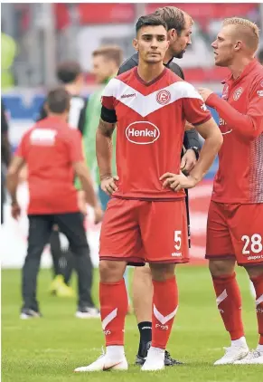  ?? FOTO: HORSTMÜLLE­R ?? Ein enttäuscht­er Abwehrchef nach dem 1:2 im ersten Heimspiel gegen den FC Augsburg. Am Arm trägt KaanAyhan einen Trauerflor zu Ehren des gestorbene­n Ex-Managers Wolf Werner. Im Hintergrun­d diskutiere­n Stürmer Rouwen Hennings (re.) und Co-Trainer Thomas Kleine überdas Spiel.