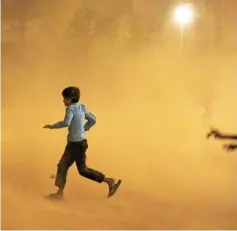  ?? — Reuters photo ?? A boy runs for cover during a dust storm in New Delhi.