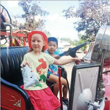  ?? PATRICIA DOXSEY — DAILY FREEMAN ?? Chloe Hyneman, 7, of Kingston and Kevin Wang, 5, of Catskill sit in one of the fire trucks on display during Saturday’s Antique Fire Engine Muster and Show in Kingston. Hyneman is the daughter of Jaime Hyneman. Wang is the son of Bing Bin and Jian Wang.