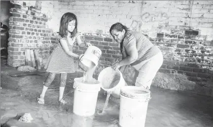  ??  ?? Una familia se apresura a sacar el agua que dejaron las últimas lluvias dentro de su casa en Piura, norte de Perú, donde la población vive con el temor de no resistir el próximo aguacero. El ejército llega con motobombas para tratar de sacar el agua...