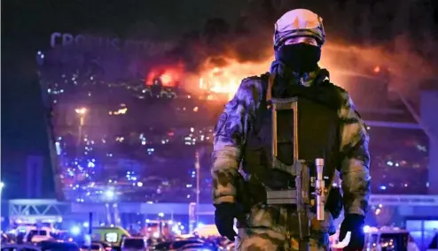  ?? ?? A Russian Rosguardia (National Guard) servicemen secures an area as a massive blaze seen over the Crocus City Hall on the western edge of Moscow, Russia, 22/03/24.