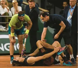  ?? CHRISTOPHE ARCHAMBAUL­T/GETTY ?? Alexander Zverev is assisted as he lies on the court after injuring his ankle during the French Open semifinal against Rafael Nadal on Friday.