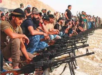  ?? AFP ?? Rebel fighters sit with their machine guns during a military parade near the southern city of Dara’a on Thursday. Regime forces are preparing for a final assault on the south.