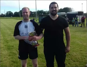  ??  ?? Paul Dwyer, son of the late Richie, presents the silverware to Alan Diskin after Corach Ramblers’ victory over Fastnet Rovers in the Richie Dwyer Over-35 shield final in Duncannon on Saturday.