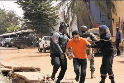  ??  ?? HOSTAGE: Mali trooper assist a hostage, center, to leave the scene, from the Radisson Blu hotel to safety after gunmen attacked the hotel Friday in Bamako, Mali. Islamic extremists armed with guns and throwing grenades stormed the Radisson Blu hotel in...