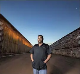  ??  ?? JESUS TARAZON, a veterinary assistant who commutes daily from his home in Naco, Mexico, to work in Bisbee, stands between the new and old border walls.