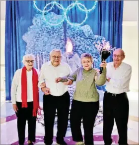  ?? SUBMITTED PHOTO — PETER BECKER COMMUNITY ?? From left, torchbeare­rs Margaret Reed, Gerry Rosenberge­r, Madelyn O’Brien and Roy Feiss stand in front of the Olympic torch at the Peter Becker Community Senior Winter Olympics opening ceremonies.