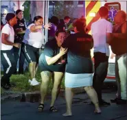  ?? ELLEN M. BLALOCK — THE ASSOCIATED PRESS ?? A woman reacts as emergency response crews move wounded people to ambulances after multiple people were shot at a party Saturday in Syracuse, N.Y.