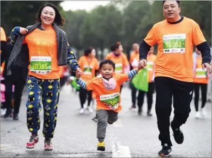  ?? WANG QUANCHAO / XINHUA ?? A family takes part in a 5-kilometer race in Chongqing on Nov 29.