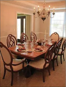  ??  ?? A wide opening leads into the formal dining room, where the elongated octagonal tray ceiling is framed with moldings and centered with a smaller version of the entry’s chandelier.