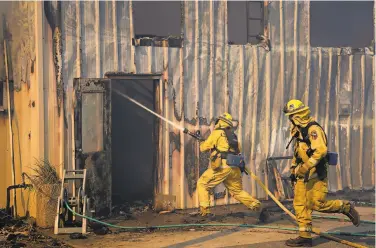  ??  ?? Cal Fire personnel fight flames in a building on Upper Service Road near California Maritime Academy.