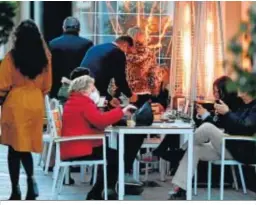  ??  ?? Una familia toma un café en un bar junto a una gran estufa.