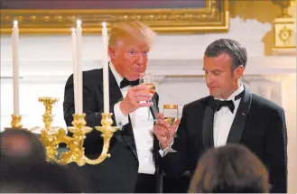  ?? Susan Walsh ?? The Associated Press President Donald Trump and French President Emmanuel Macron toast in the State Dining Room on Tuesday during a state dinner at the White House.