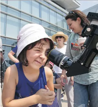  ?? PHOTOS: WAYNE CUDDINGTON ?? Claire Girard, 7, looks through a telescope equipped with a solar filter.