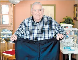  ?? JOHN RENNISON THE HAMILTON SPECTATOR ?? Ed Tymkow holds up a pair of dress pants that wore when he weighed 246 pounds last summer, before he started working out. He is now down to 200 pounds. His goal is 195.
