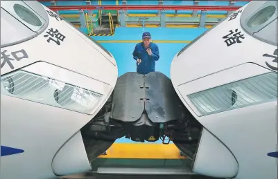  ?? TANG KE /FOR CHINA DAILY ?? A worker guides bullet trains at a rail depot in Qingdao, Shandong province, in preparatio­n for the Spring Festival travel peak.