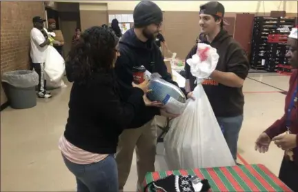  ?? BRIANA CONTRERAS — THE MORNING JOURNAL ?? Robert Szababos, 19, a volunteer at a Salvation Army Christmas event, hands over a turkey and bag of Christmas gifts Dec. 19 to John and Siomara Corey, of Lorain, at 2506 Broadway in Lorain. The event provided over 600 toys, Christmas gifts and a bag of food for 300 families.