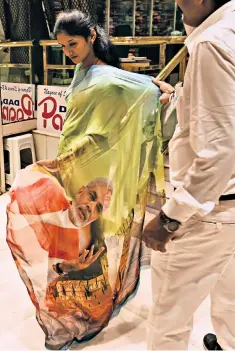  ??  ?? A woman tries on a sari bearing the image of Narendra Modi, India’s prime minister