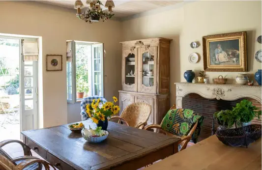  ??  ?? ABOVE The kitchen ceiling is boarded with rustic planks and the walls are painted in String by Farrow & Ball. The reclaimed fireplace has the same carved sunflower motif as the marriage cabinet in the corner, suggesting that both came from the Normandy area. LEFT Gloria uses the marriage cabinet to display her collection of antique French ceramics. The chair is upholstere­d in a 19th-century blue and white check. FACING PAGE
The dinner plates are 19th-century and the antique monogramme­d napkins were dyed to a soft grey by Polly Lyster.