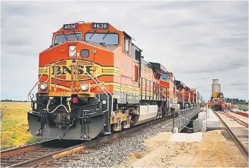  ??  ?? A westbound intermodal train passes by maintenanc­e-of-way workers who are using a track laying machine to construct a second main line on the Burlington Northern Santa Fe (BNSF) Railway Co. Southern Transconti­nental line in Alva, Oklahoma,on Aug 19,...