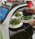  ?? ?? Das Küchenpers­onal lädt den Transportr­oboter voll und schickt ihn dann in den Speisesaal, wo die Bedienung die Salate den Gästen serviert.