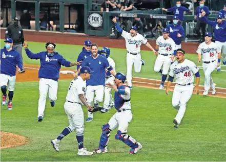  ??  ?? The Los Angeles Dodgers race out of their dugout to celebrate their 3-1 win over the Tampa Bay Rays in Game 6 of the World Series on Tuesday in Arlington, Texas. [AP PHOTO/ TONY GUTIERREZ]