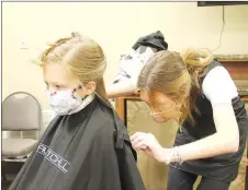  ?? LYNN KUTTER ENTERPRISE-LEADER ?? A hairstylis­t with Paul Mitchell The School in Fayettevil­le gives a free haircut to Ava Henry, 6, of Farmington, at the Farmington Back to School Bonanza. Ava will be in first grade at Folsom Elementary School this year.