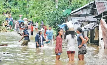  ??  ?? Villagers wade through a flooded street in Brgy Calingatng­an, in Borongan, on easterm Samar in central Philippine­s.