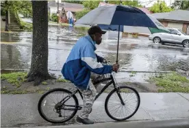  ??  ?? A man rides a bicycle as rain from Tropical Storm Bertha flooded streets in Charleston, South Carolina on 27 May 2020. Photograph: Matthew Fortner/AP