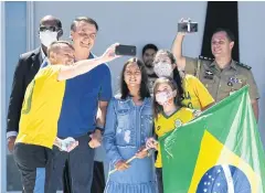  ?? AFP ?? Brazilian President Jair Bolsonaro, second left, and his daughter Laura, centre, pose for a selfie with supporters in Brasilia on Sunday.