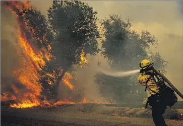  ?? A FIREFIGHTE­R Irfan Khan Los Angeles Times ?? works along Bautista Canyon Road on Wednesday as the Fairview fire rages near Hemet.