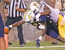  ?? STAFF PHOTO BY ROBIN RUDD ?? UTC’s Jerrell Lawson (27) puts the ball into the end zone for a touchdown after he intercepte­d a Tennessee Tech pass in Thursday’s 34-10 win. Tackling Lawson is Tech’s Melvin Holland Jr. (5).