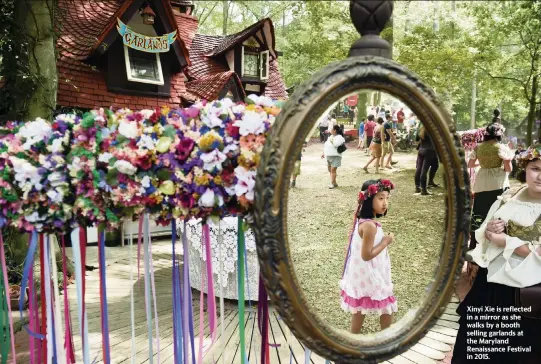  ?? MATT MCCLAIN The Washington Post, file ?? Xinyi Xie is reflected in a mirror as she walks by a booth selling garlands at the Maryland Renaissanc­e Festival in 2015.