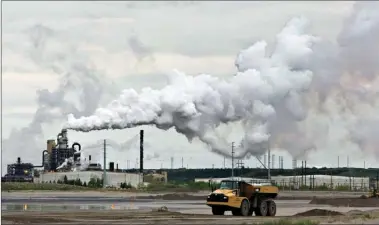  ?? The Canadian Press ?? A dump truck works near the Syncrude oil sands extraction facility near the city of Fort McMurray. Canadians will find out exactly how they will be compensate­d for the upcoming federal carbon tax.