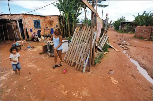  ?? (AP/Eraldo Peres) ?? A young woman sweeps the dirt path outside her home March 22 in the Sol Nascente neighborho­od of Brasilia, Brazil.