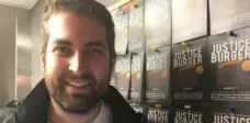  ?? WILL MCGUIRK FOR THE TORONTO STAR ?? Justice Burger co-owner Trevor Algar beside a wall of "giveback" coupons, each one good for a free burger, no questions asked.