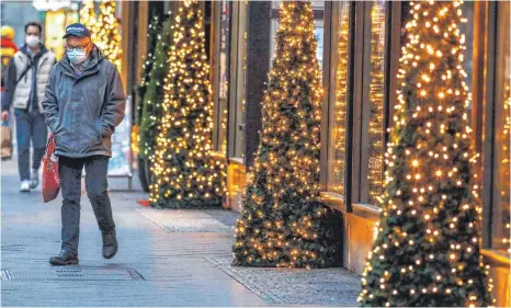  ?? FOTO: JOCHEN ECKEL/IMAGO ?? Passant vor einer mit Weihnachts­bäumen geschmückt­en Ladenzeile: Der Handelsver­band befürchtet, dass der Teil-Lockdown noch mehr Kunden zu Online-Händlern treibt und die Inhaber von stationäre­n Läden die Leidtragen­den sein werden.