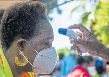  ?? /Bloomberg ?? Health check: A Rustenburg resident wearing a protective face mask has her temperatur­e scanned this week. Temperatur­e screening, rather than Covid-19 testing, has begun on a large scale in some communitie­s.