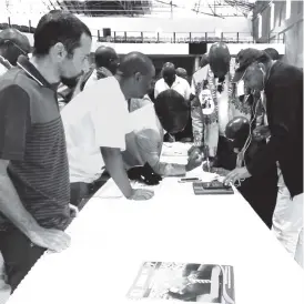  ??  ?? Zanu-PF members check for their names with the Midlands Province chairperso­n Engineer Daniel MacKenzie Ncube yesterday in preparatio­n for primary elections on Sunday