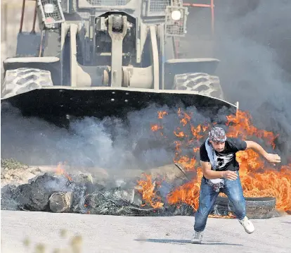  ??  ?? Ein palästinen­sischer Demonstran­t flüchtet bei Protesten nahe Khobar bei Ramallah vor einem Räumfahrze­ug der israelisch­en Armee, das brennende Straßenspe­rren entfernt.