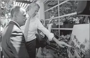  ?? ALAN DIAZ/AP PHOTO ?? New York City Mayor Bill de Blasio, right, points to a photo Friday as Miami Beach Mayor Philip Levine looks on during a tour showing where Levine’s city has raised streets and installed pumps to combat rising tides.