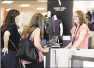  ?? Chuck Burton / Associated Press file photo ?? Cashier Liz Moore, right, checks out customers Christie Meeks, center, and Lisa Starnes, left, at a Kohl’s store in Concord, N.C.