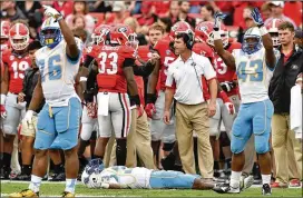  ?? BRANT SANDERLIN / AJC 2015 ?? Southern University players motion for help for wide receiver Devon Gales after he was hit by Bulldogs kicker Marshall Morgan on a kickoff return during the Sept. 26, 2015, game in Athens.