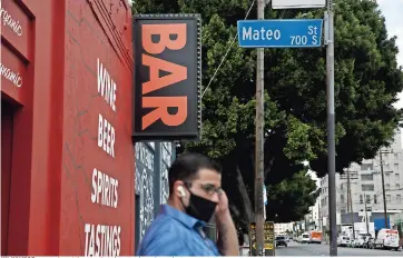  ??  ?? Un hombre espera el autobús cerca de un bar cerrado por la pandemia