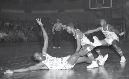  ?? THE COMMERCIAL APPEAL FILES ?? March 8, 1953: Part of the Harlem Globetrott­ers routine is the playing of a baseball game right in the middle of the basketball contest. Goose Tatum, after whacking a “hit” into the stands, slides in under “catcher” Ermer Robinson. “Umpire” Clarence Wilson calls Goose safe. The action was part of the day-night doublehead­er the Trotters played at Ellis Auditorium.